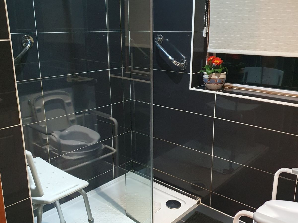 walk in shower with grab rails and shower chair, with non slip mat for safer bathroom use